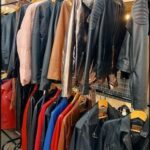 a grove of leather jackets hanging on a rack in a clothing store