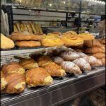 arafed display of baked goods in a bakery with a woman looking at them