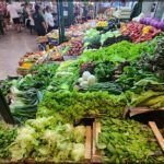 arafed display of vegetables in a market with people in the background