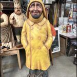 arafed statue of a man in a yellow coat and hat
