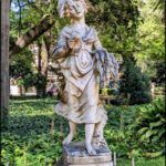 arafed statue of a woman holding a bird in a park