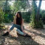 araffe sitting on the ground in the woods with her legs crossed