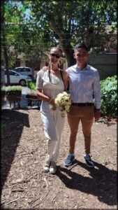 bride and groom standing in a garden with a tree in the background