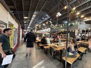 people are eating at tables in a large indoor market