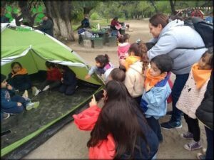 people are gathered around a tent in a park with a green tent