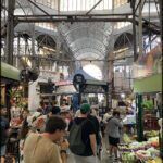 people are shopping in a large indoor market with a glass ceiling