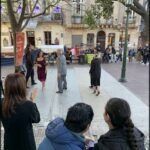 people are sitting on a bench in a city square