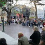 people are sitting on benches watching a man perform a street show
