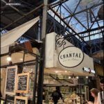 people are standing in a food market looking at their cell phones