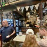 people are standing in a restaurant with a man standing at the counter