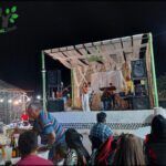 people sitting at tables in a restaurant watching a man on stage