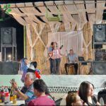 people sitting at tables in front of a stage with a man on the stage