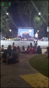 people sitting on the ground watching a man on stage