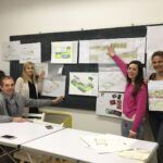 several people are standing around a table with drawings on it