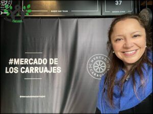 smiling woman in blue scarf standing in front of a sign