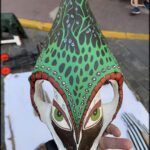someone is holding a mask with a green and black design