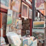 there are many paintings on display outside of a store