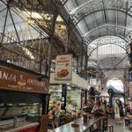there are many people walking through a market with tables and benches