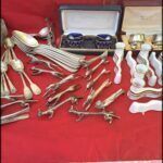 there are many silverware items on a table with a red table cloth