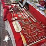 there are many silverware on a table with red cloth