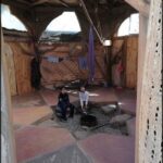 there are two people sitting on the ground in a hut