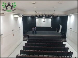 there are two people standing in a large auditorium with a projector screen