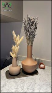 there are two vases with dried plants on a tray