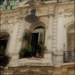there is a clock on the building that is decorated with plants