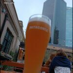 there is a glass of beer sitting on a table in front of a building