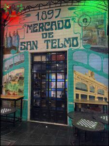 there is a mural on the side of a building with a bench and table