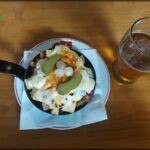 there is a plate of food on a table with a glass of beer