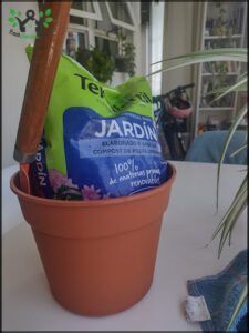 there is a potted plant with a bag of gardening seed and a shovel