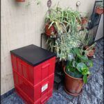there is a red box sitting next to a potted plant