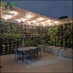 there is a table and chairs on a patio with a wall of plants
