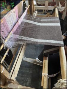 there is a woman sitting at a table with a weaving machine