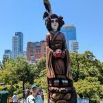 there is a woman standing next to a totema statue in a park