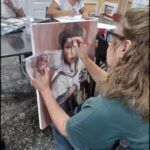 woman sitting in a chair painting a picture of a child