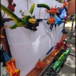 A collection of colorful and creative monster heads hang from a wooden structure.