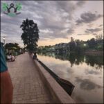 A group of people sit on a brick walkway overlooking a body of water, enjoying the view and each other's company.