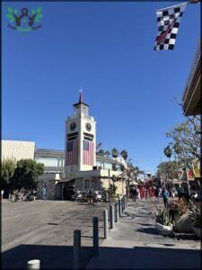 A large clock tower with a flag on top, surrounded by palm trees.
