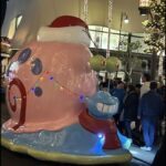 A large pink and blue snail with a Santa hat on its head.