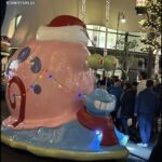 A large pink and blue snail with a Santa hat on its head.