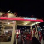 A lit-up gas station with a red neon sign that reads "Gilmore."
