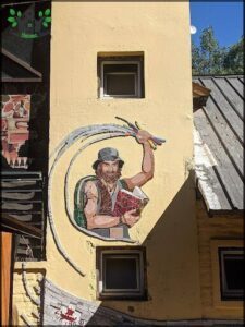A man is depicted on a wall, holding a book and a pair of scissors.