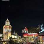 A nighttime city scene with a lit-up Ferris wheel and a lit-up Christmas tree.