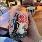 A person is holding a coffee cup with a picture of a dog and a cat on it.