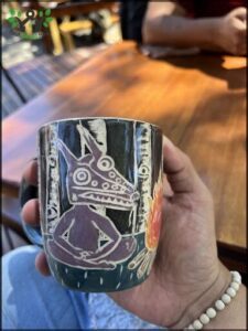 A person is holding a mug with a picture of a face on it.