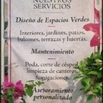 A sign advertising a maintenance service is displayed in front of a potted plant.