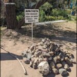 A sign in a foreign language is posted in front of a pile of rocks.