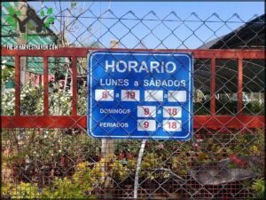 A sign in Spanish is posted on a fence, indicating the hours of operation for a business.